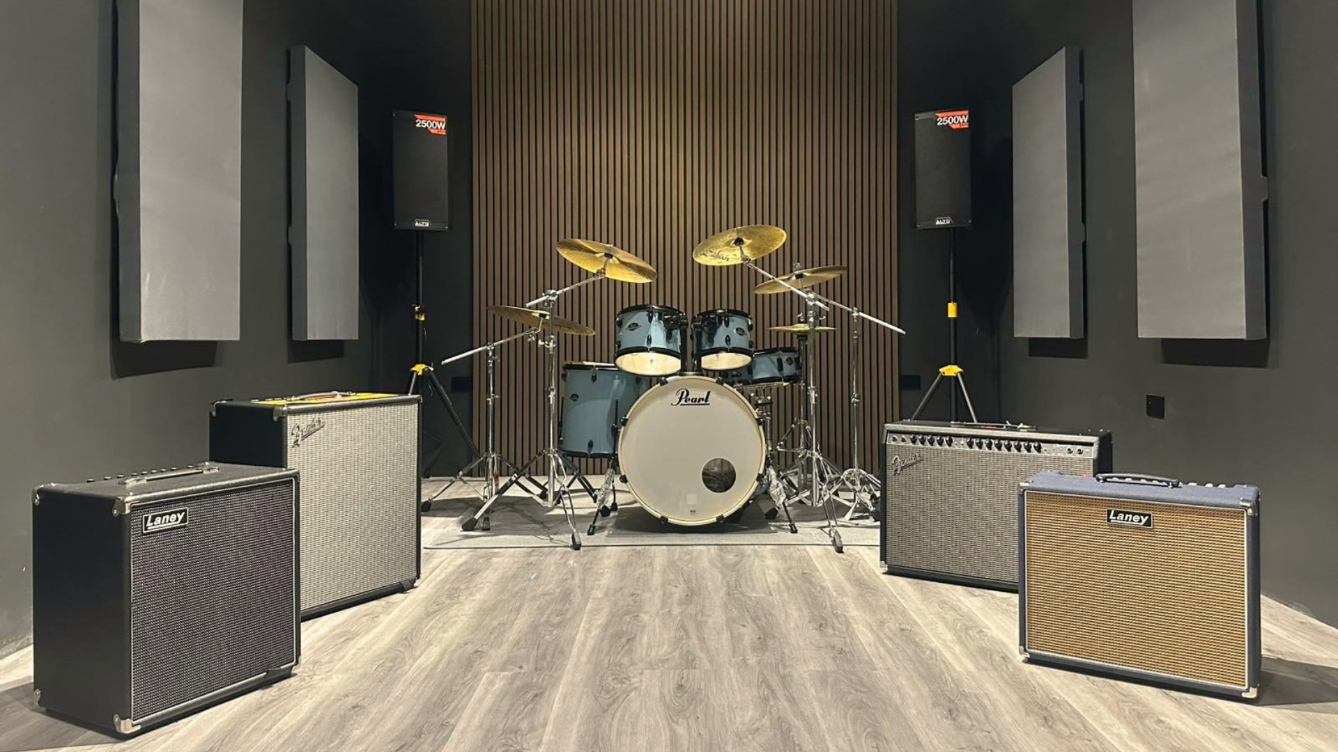 Heywire rehearsal room with a drum kit, guitar and bass amps, and PA speakers